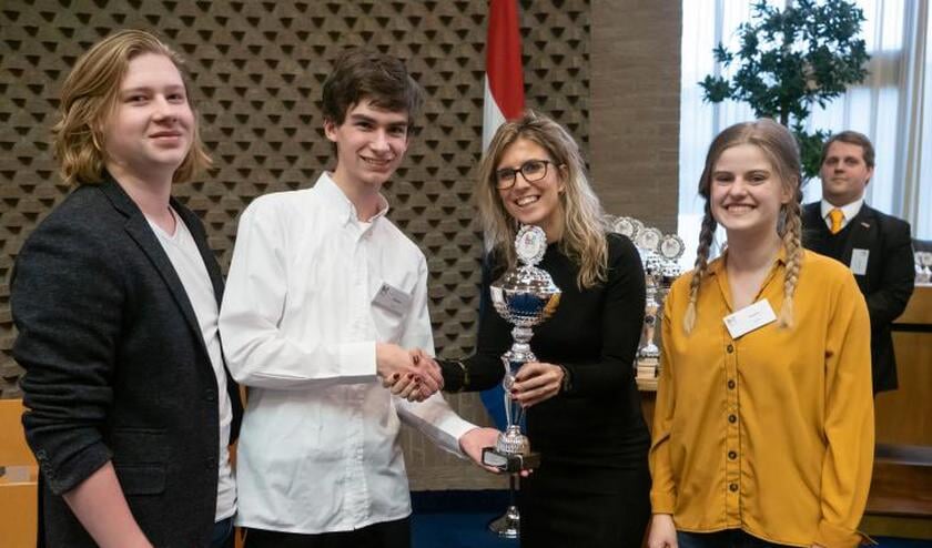 De drie finalisten van het Kaj Munk College ontvangen de beker van hockeykampioen Lisanne de Roever.