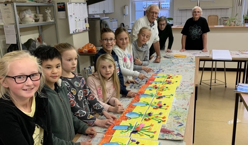 Kinderen van de Kinderclub bij hun stilleven schilderij met op de achtergrond het team docenten.