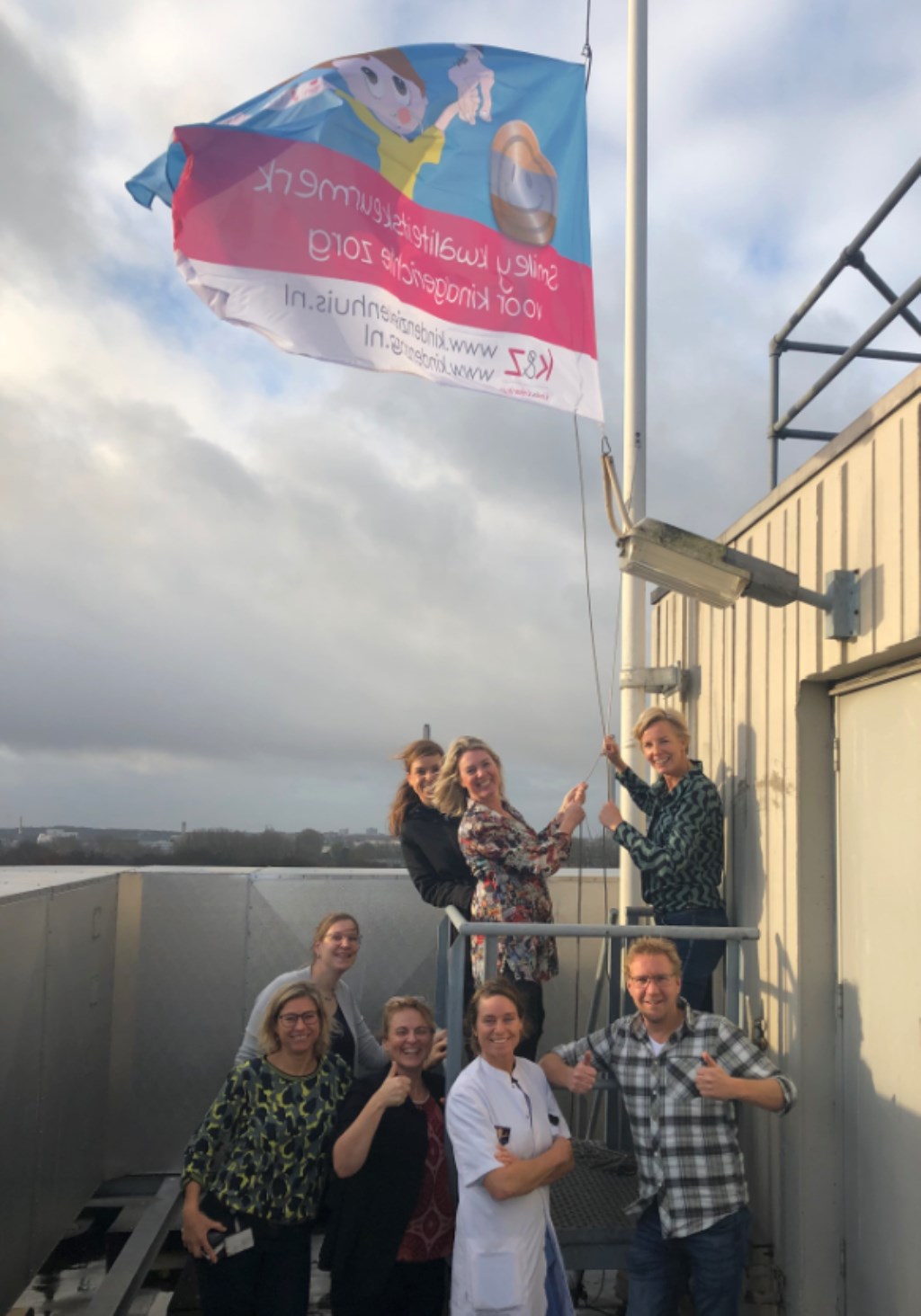 Het hijsen van de speciale Zilveren Smiley vlag op het dak van het ziekenhuis.