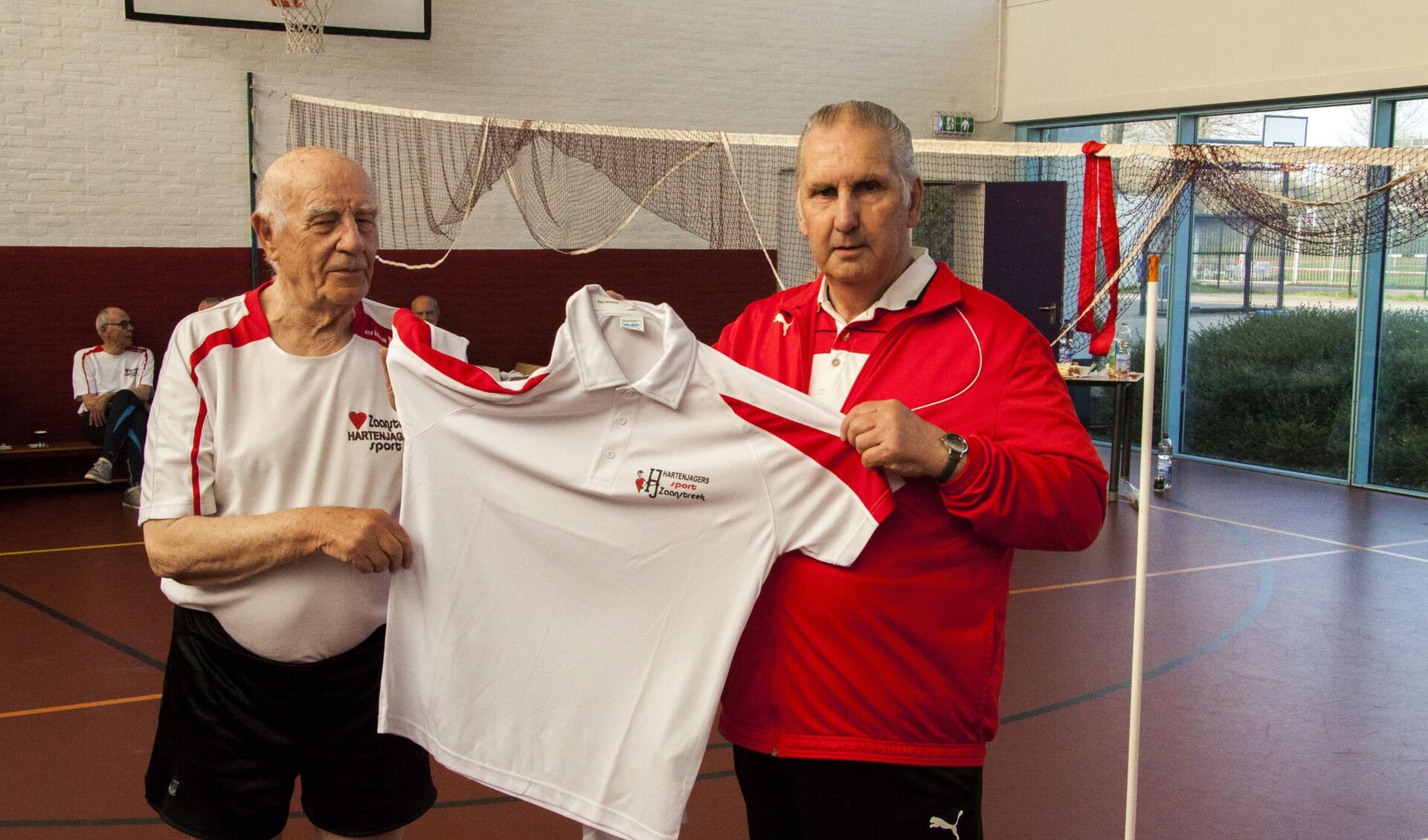 Ton Reuser (88) krijgt het eerste sportshirts uit handen van Ton Schomakers (r) voorzitter Hartenjagers Sport Zaanstreek.