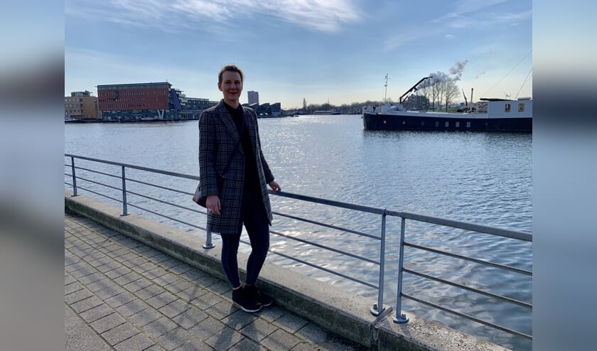 Mede-organisator Fleur Pastoors bij de toegang van Zaaneiland met op de achtergrond het schip van een van de deelnemers.
