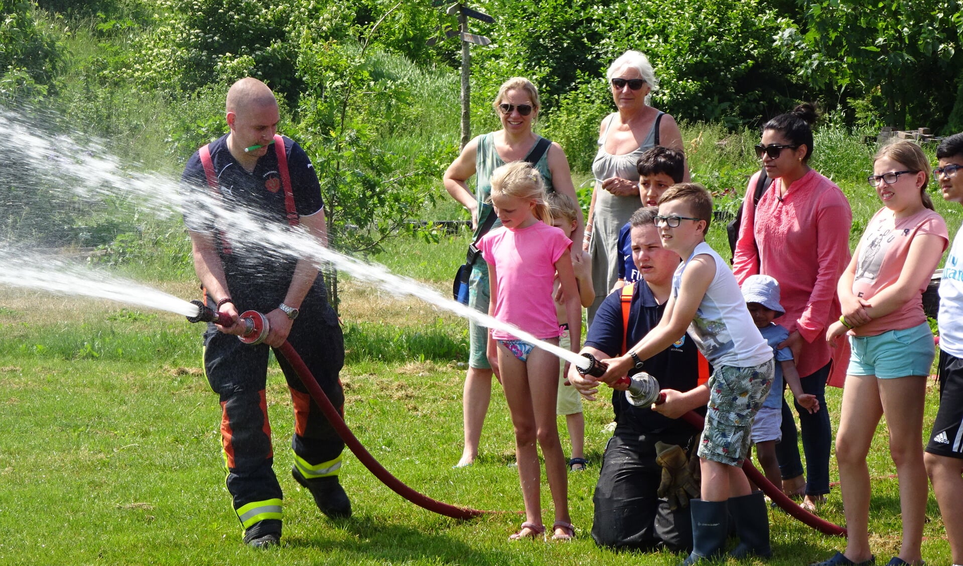 Kinderen mogen spuiten met een echte brandweerslang. 