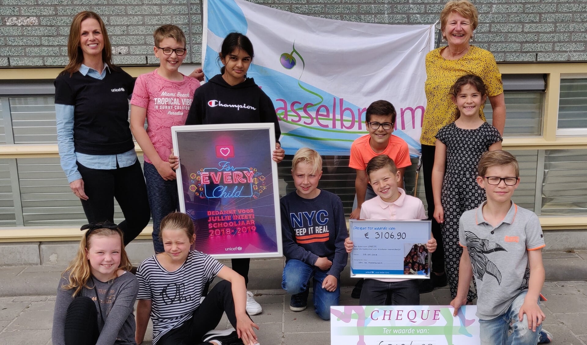 Trots hebben de kinderen van De Hasselbraam de cheque overhandigd aan Aletta Troost van Unicef (staand links).