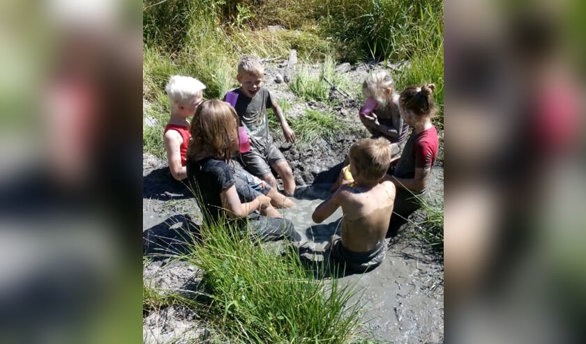 Kinderen ontdekken hoe je met modder kunt spelen. De kleren blijven niet schoon!