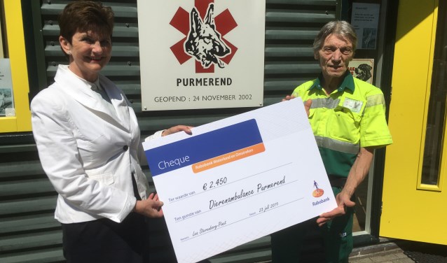 Pim Langereis van de Dierenambulance krijgt de cheque van de afscheid nemende Lea Sterenborg-Pinxt.