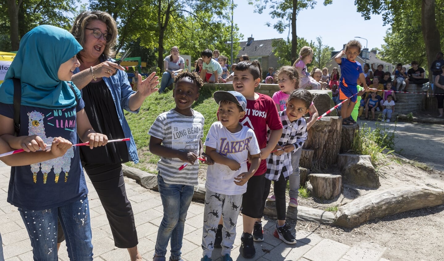 Wethouder Marjolein Steffens knipt het lint van kinderen door; het Wereldplein is geopend. 