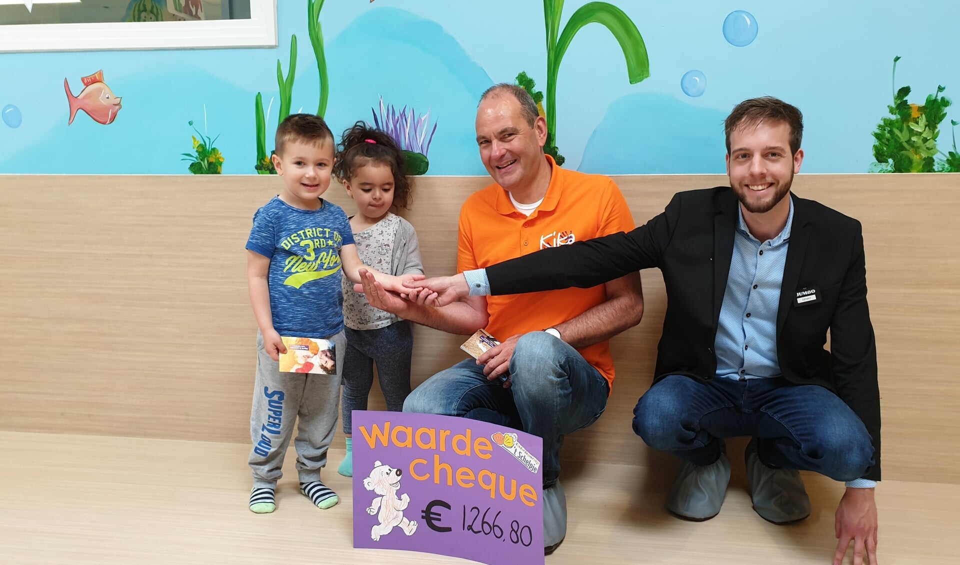 René Oud van KiKa krijgt de cheque uit handen van kindjes van 't Schelpje, Rechts Denny Laan van sponsor 'Jumbo Monique'.