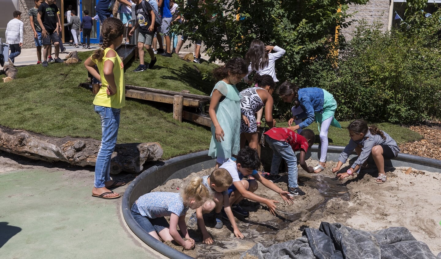 Kinderen graven een rivier in de waterzandbak. 