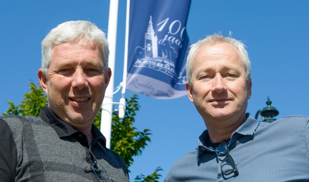 Klaas en Albert Hakvoort voor de vlag met het logo van de 100-jarige.