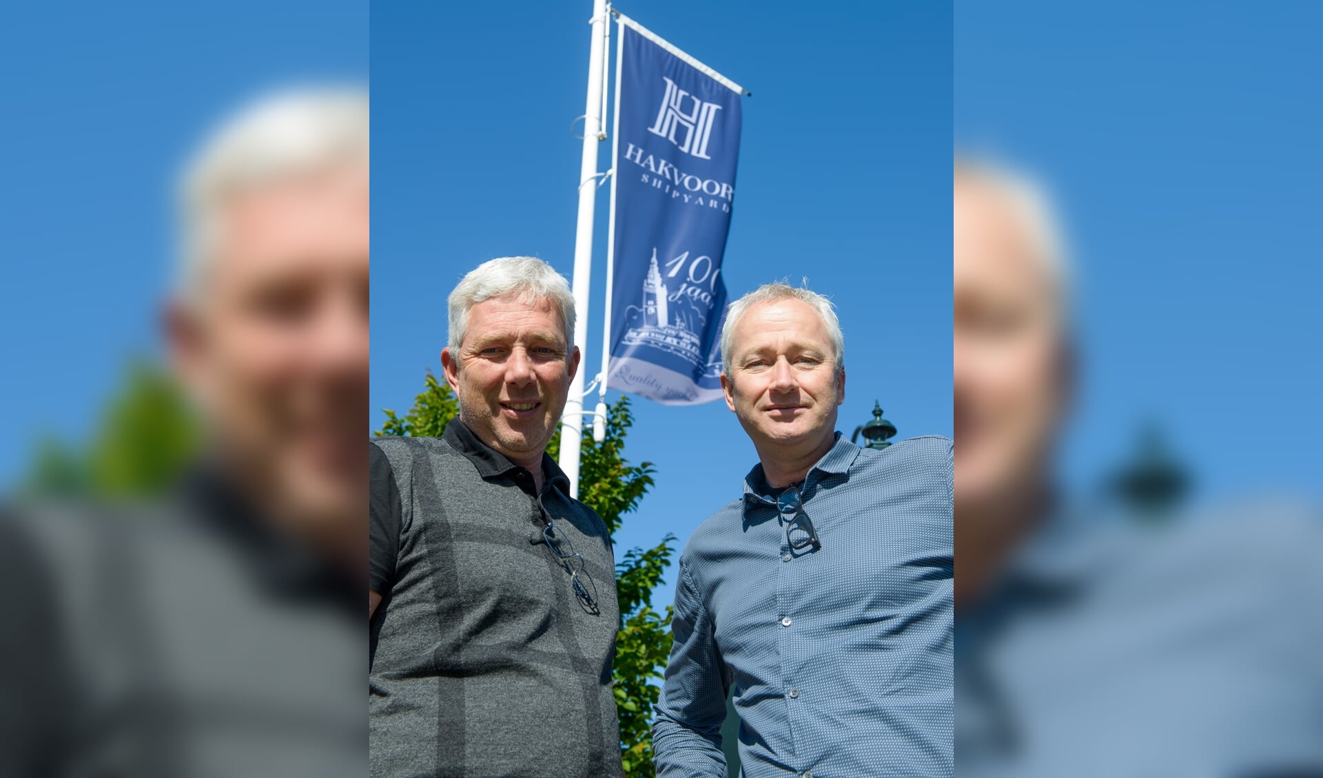 Klaas en Albert Hakvoort voor de vlag met het logo van de 100-jarige.  