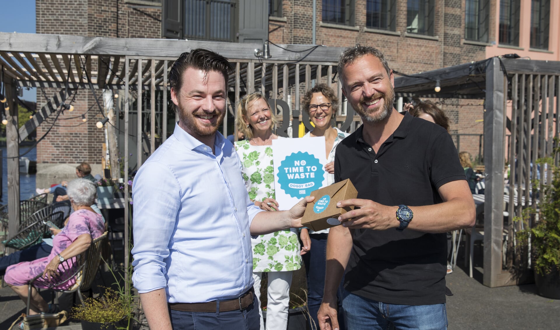 Links wethouder Robbert Berkthout die Frank van Baaren, eigenaar van restaurant Frisk aan het Spaarne en bestuurslid Koninklijke Horeca Nederland, het eerste exemplaar aanbiedt.