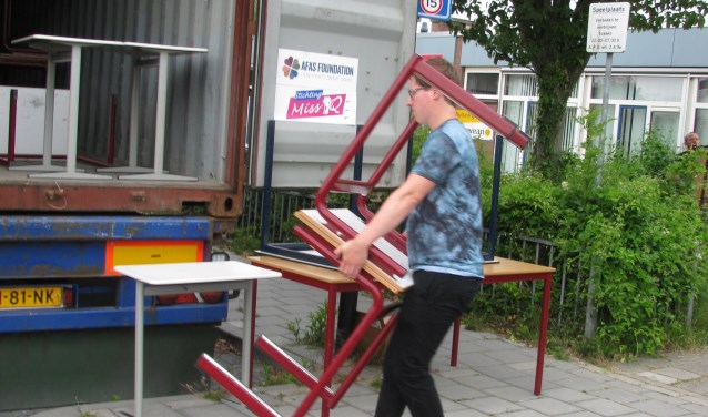 Schoolmeubilair wordt in de vrachtcontainer geladen.