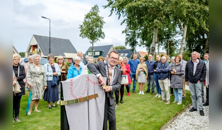 Wethouder John Does gaat over tot de onthulling van het kantelbare informatiebord.