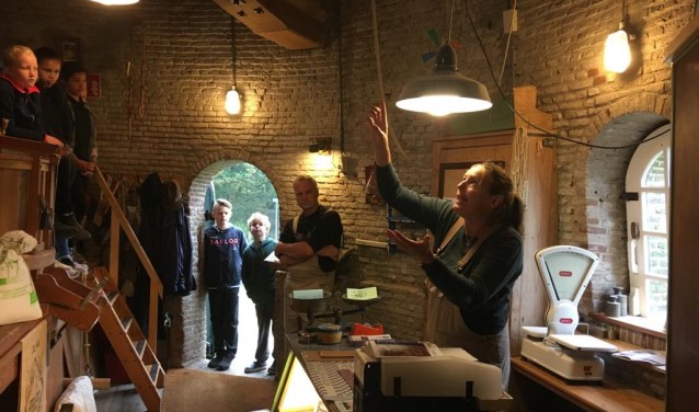 Vrijwillig molenaar Tessa Krop met leerlingen groep 7 op bezoek in de molen, hier op 'de maalvloer