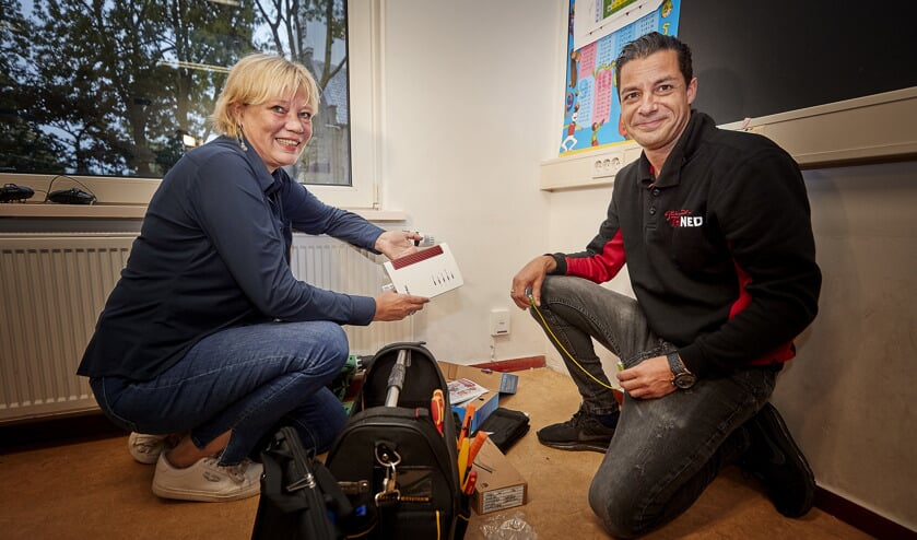 Samen met een monteur van Trined activeert directeur Mariska Buizer (l) van OBS Prinses Beatrix de eerste glasvezelaansluiting in Kwadijk.