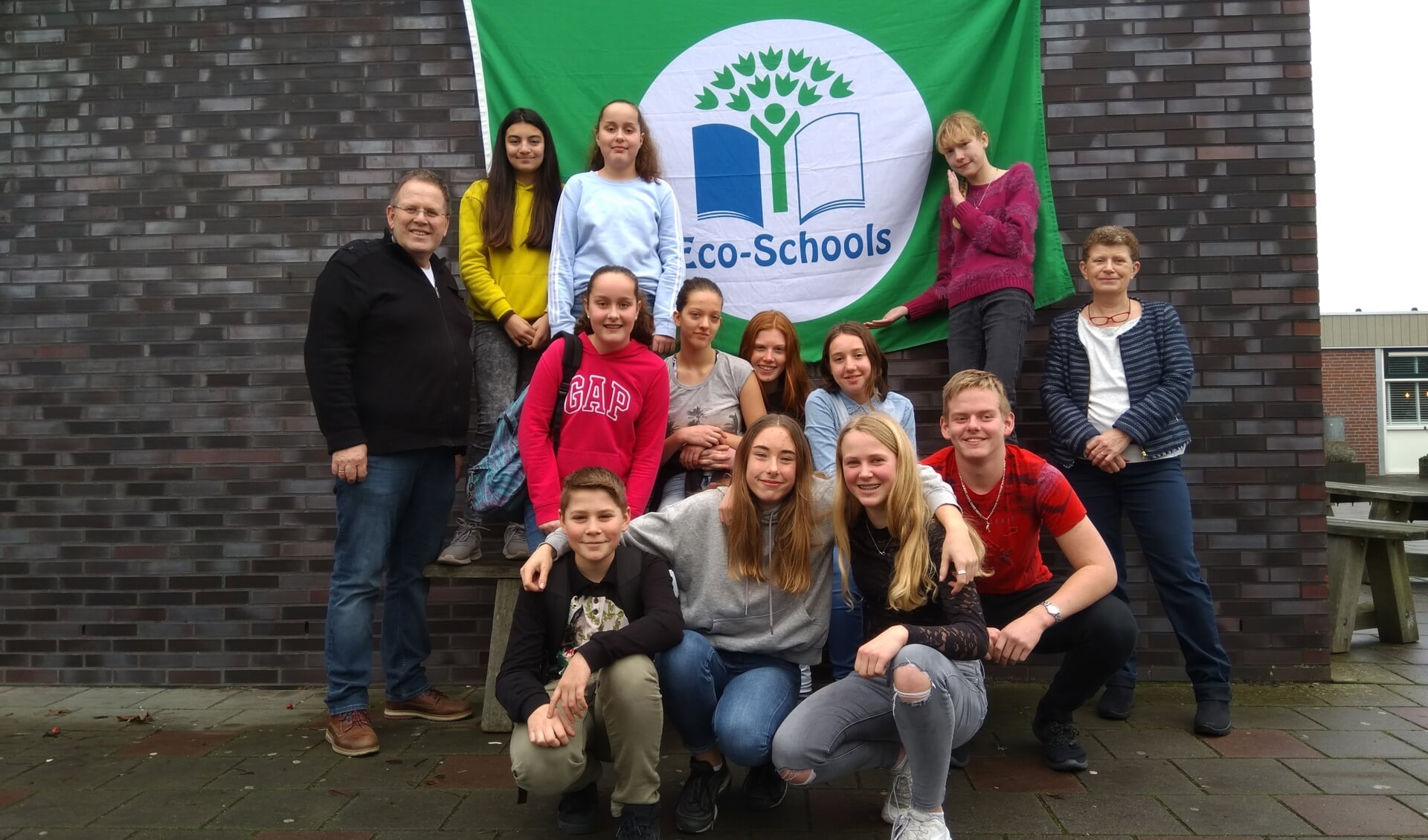 Een deel van eco-team The Greenies poseert trots voor de Groen Vlag met hun begeleidende docenten Jacob Jeltes en Marieke Brehm)