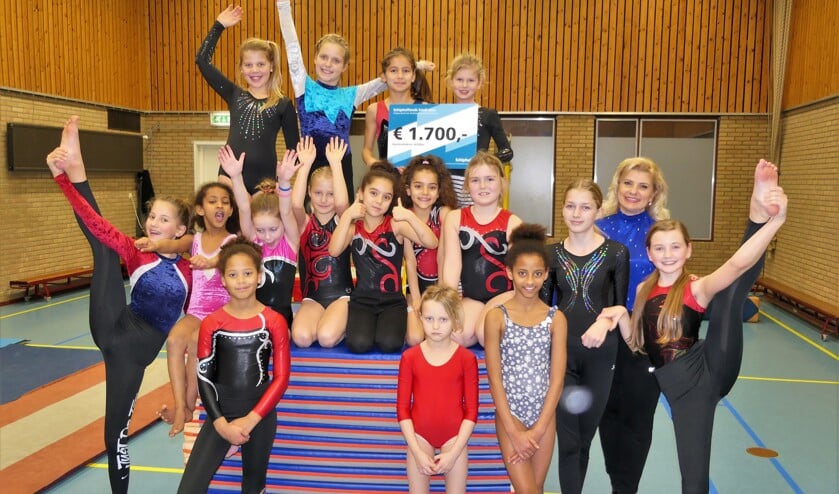 Een blijde groep kinderen met de cheque en de nieuwe matten