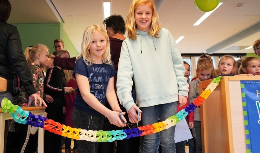 Voorleeskampioenen Fiene en Lauren knippen 'officieel' het lintje door om de bieb te openen.
