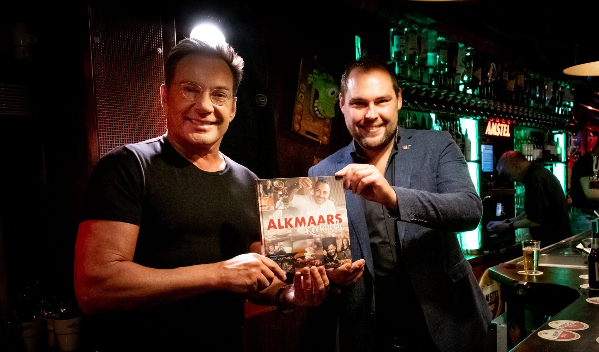 Gerard Joling neemt het eerste exemplar Alkmaar Kookboek in ontvangst.