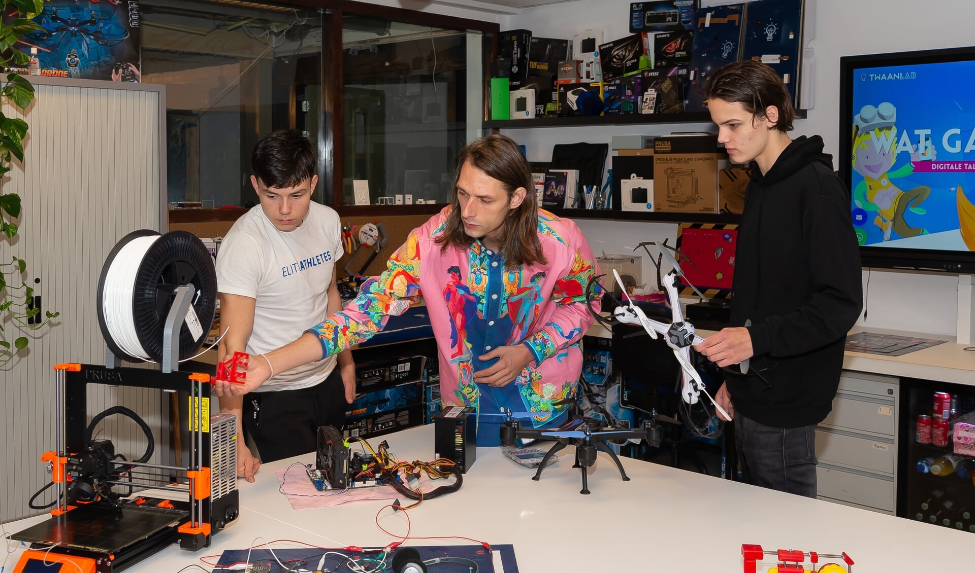 Toine Rohner (midden) geeft uitleg over drones aan Julian (links) en Mex.  