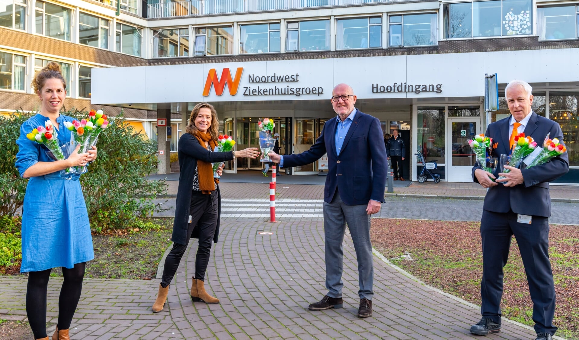 Ger Welbers en Miranda Tonkes van VVV Alkmaar/AlkmaarMarketing overhandigen de tulpen aan de Martje de Greeuw en Patrick Balvers van het NoordwestZiekenhuis. 