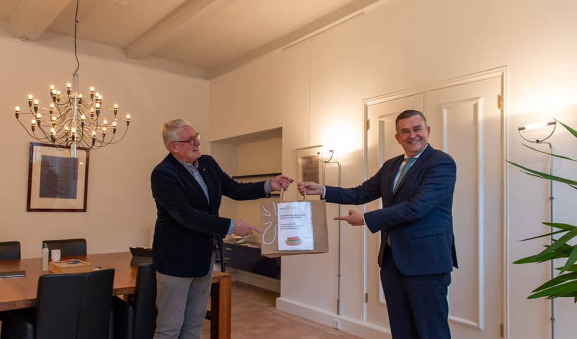 Harry van de Kuijt, voorzitter Rotaryclub Alkmaar overhandigt het eerste boerenkoolmaaltijdpakket aan Emile Roemer. 