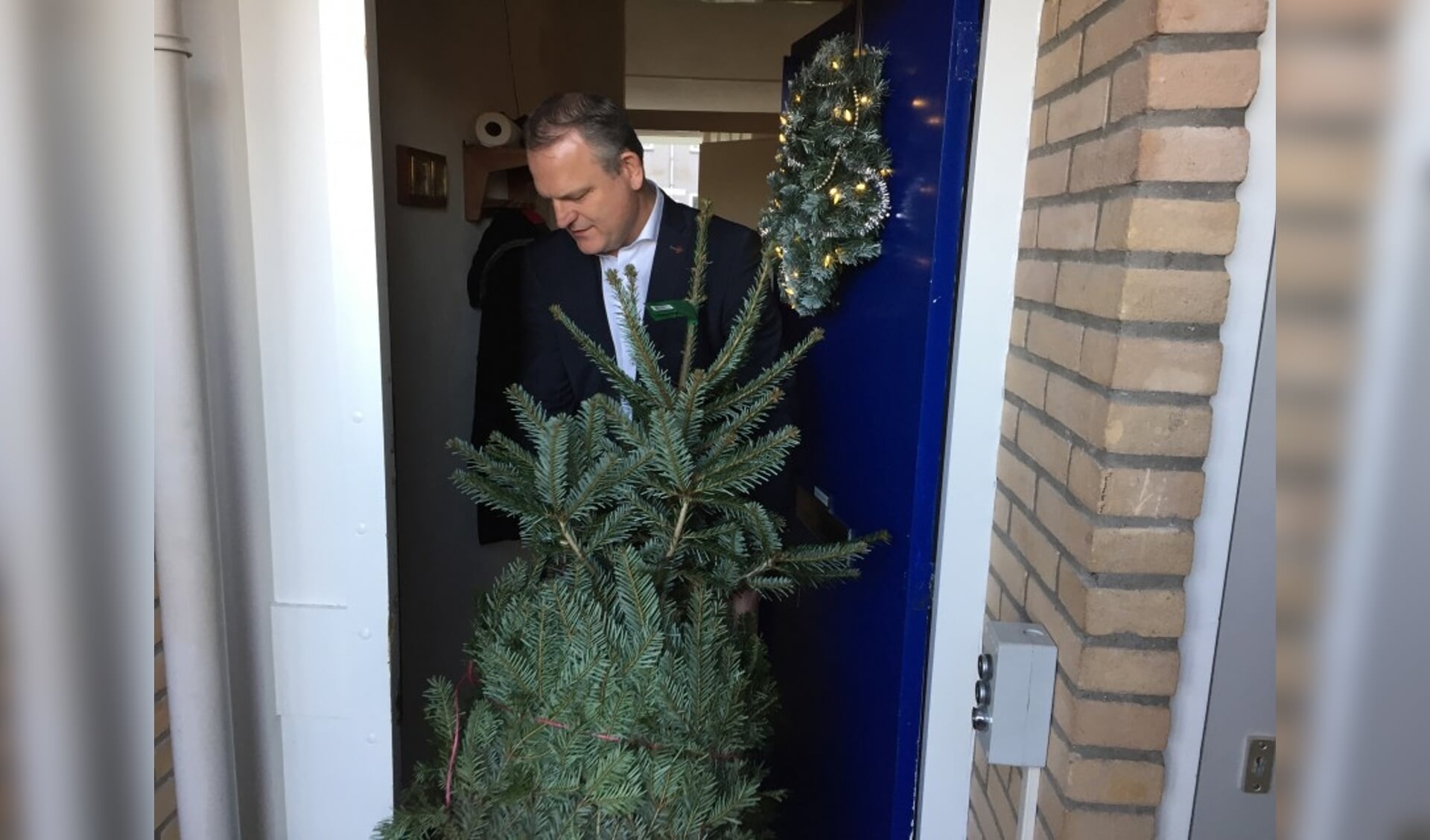 Wethouder Gerard Slegers (openbare Ruimte) brengt een kerstboom langs bij een van de bewoners van Pennemes 