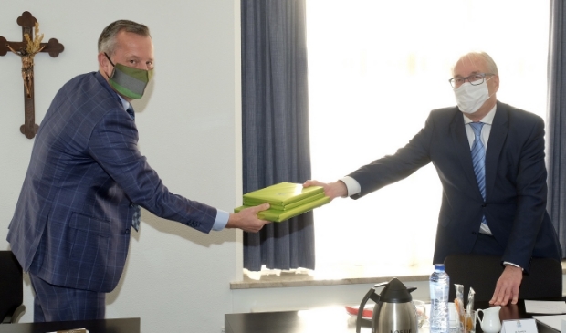 <p>Burgemeester Romeyn geeft boeken over Heiloo mee aan de Commissaris van de Koning.</p>