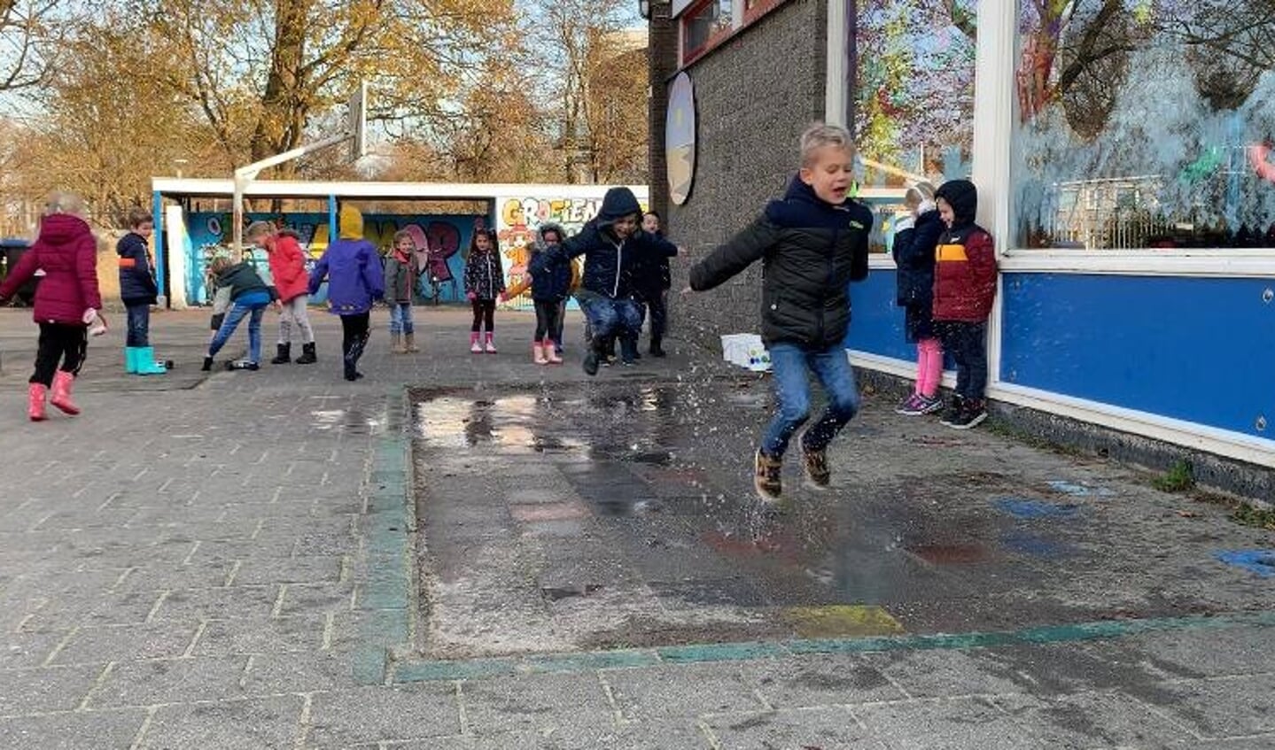 Op het schoolplein van De Kustlijn doen kinderen mee aan het NK Plassen Stampen.