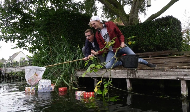 <p>Vin en Frank vissen de pakjes uit het water.</p>