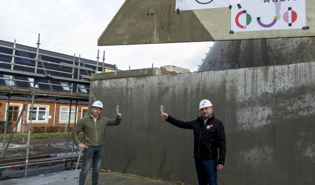 <p>De heren Bouwhuis en Van den Berg bij de woningen in aanbouw.</p>