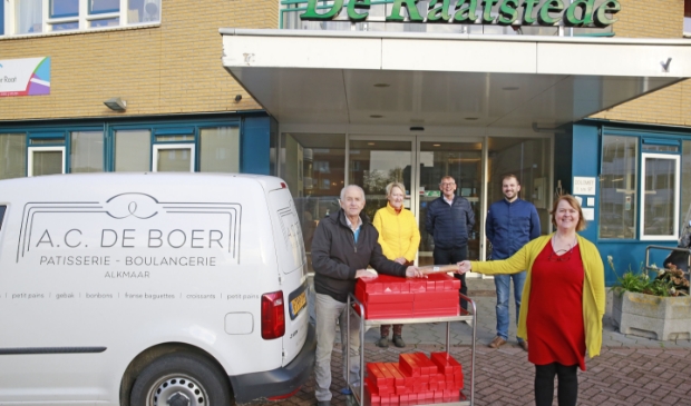 Elly Mens (r) schenkt namens de Rotary smakelijke banketstaven, Frits Weel van Gouden Dagen (l) neemt ze met liefde aan.
