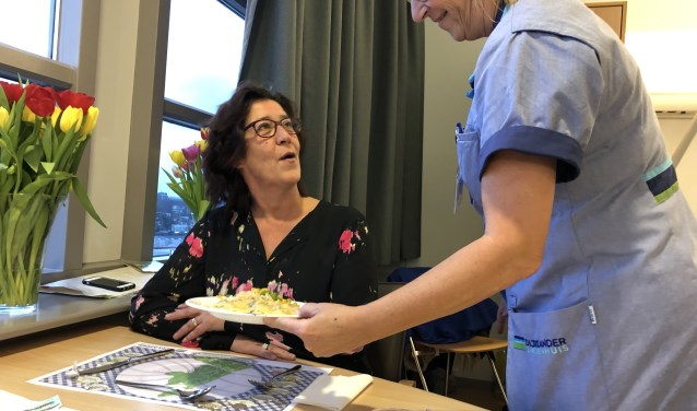 Servicemedewerker Joke Bethlehem serveert een maaltijd aan bezoeker Elisa Noordeloos.