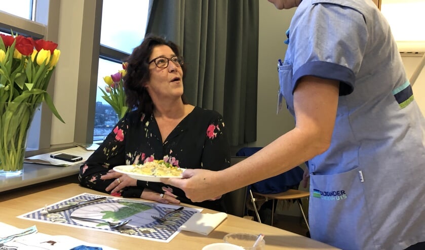 Servicemedewerker Joke Bethlehem serveert een maaltijd aan bezoeker Elisa Noordeloos.