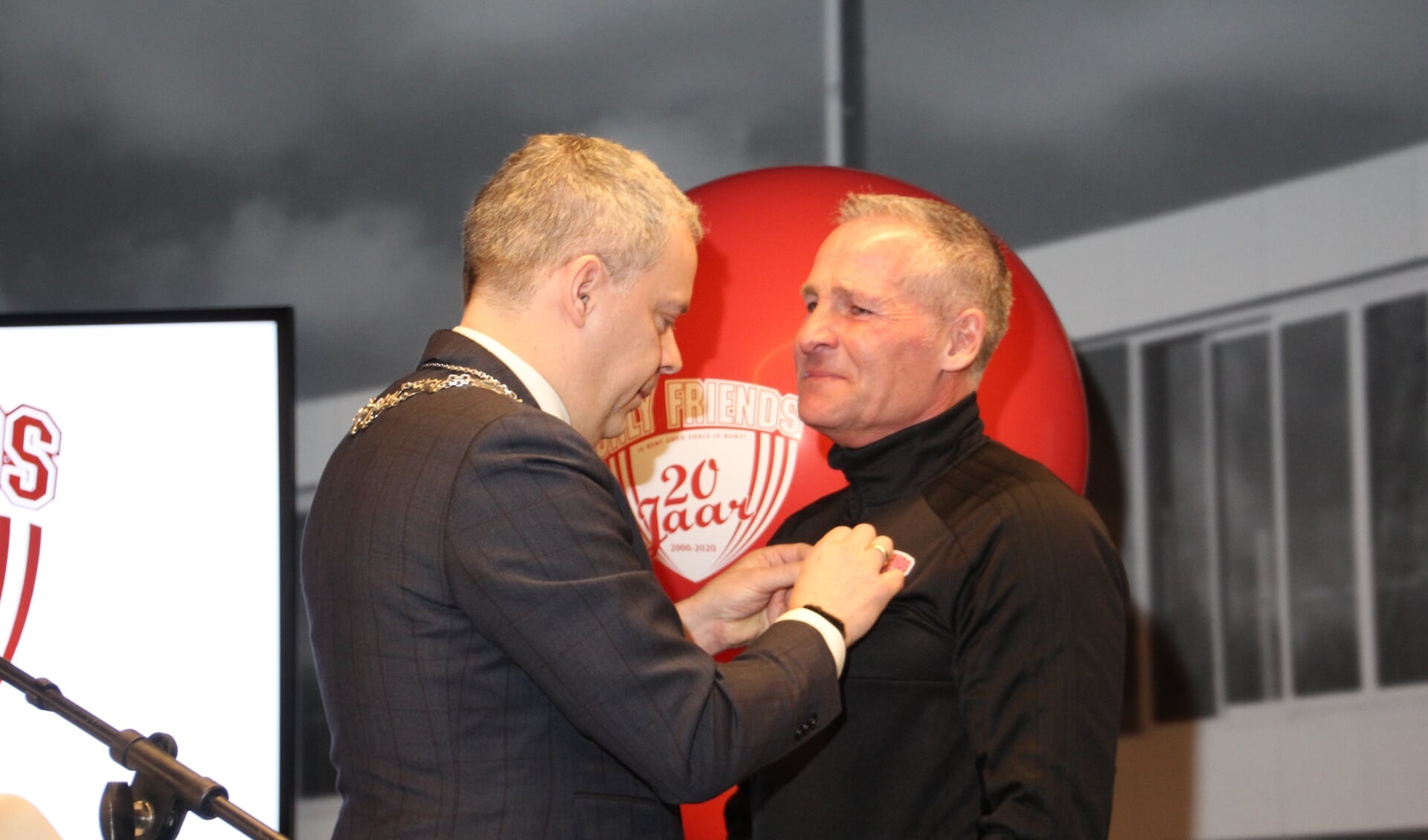 Dennis gebbink krijgt zijn onderscheiding opgespeld door de waarnemend burgemeester van Landsmeer, Dennis Straat.