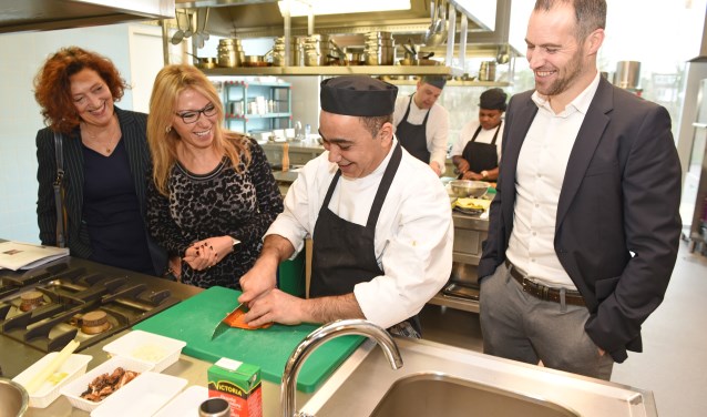 Wethouder Kholoud Al Mobayed, WerkSaam-directeur Marjolijn Dölle en Jeroen de Groot van Werkgeversservicepunt Noord-Holland Noord zien hoe deelnemers groente voor de pasta bereiden.