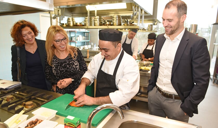 Wethouder Kholoud Al Mobayed, WerkSaam-directeur Marjolijn Dölle en Jeroen de Groot van Werkgeversservicepunt Noord-Holland Noord zien hoe deelnemers groente voor de pasta bereiden.