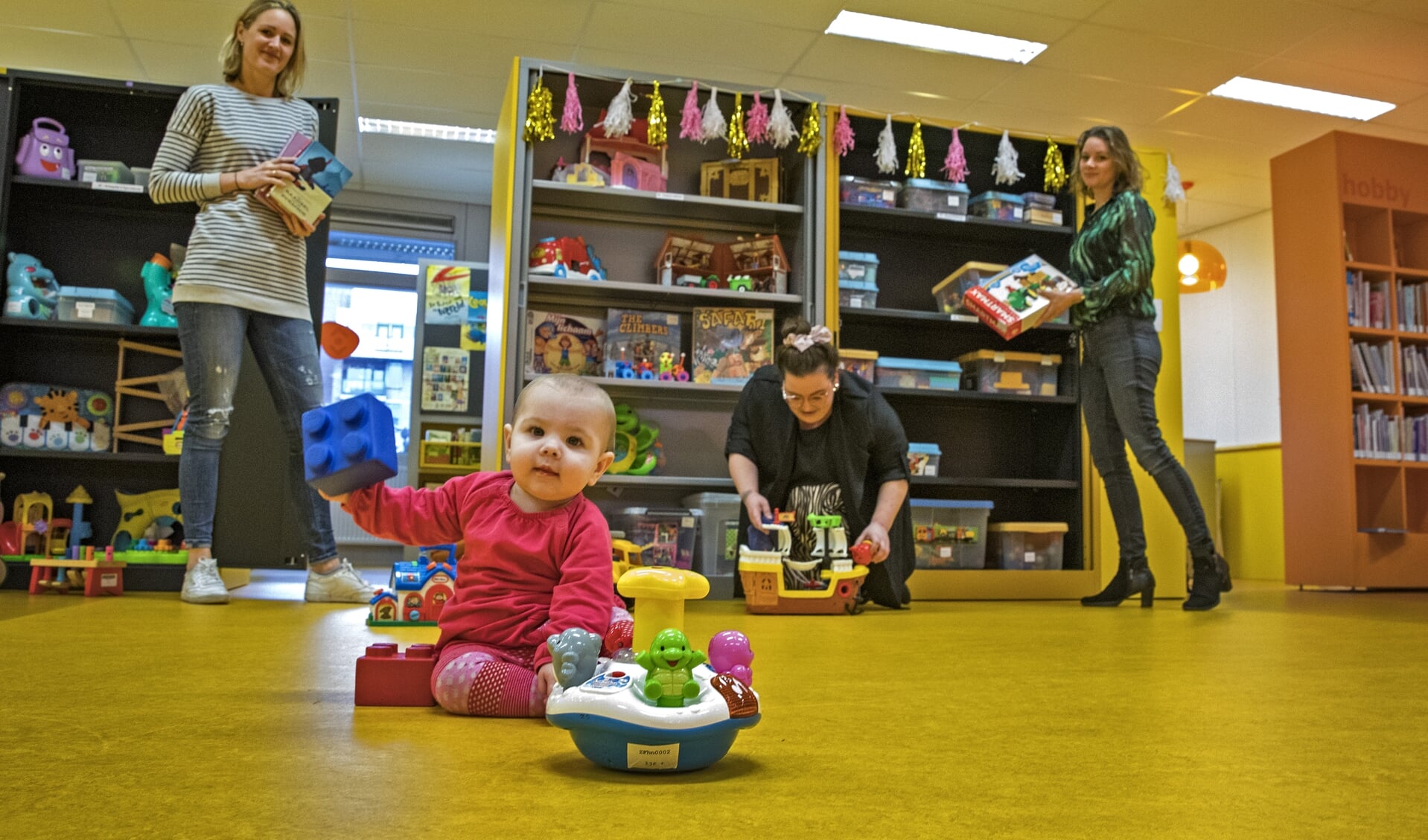 Elivia heeft het naar haar zin in de nieuwe speelotheek in bibliotheek Kersenboogerd. Op de achtergrond Iris de Snaijer, Daphne Spil en Leonie Borgemeester (v.l.n.r.).