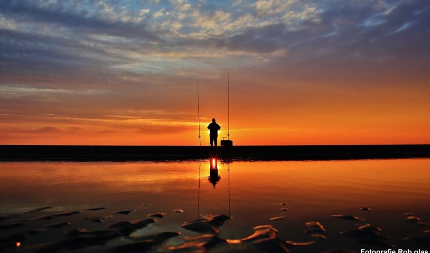 Een visser die aan de vloedlijn staat te genieten