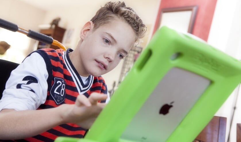 Slechtziende jongen kijkt op iPad.