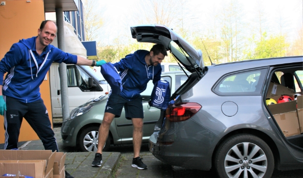 Freek de Kort en Remy Kluvers laden de auto vol gratis Meedoen-tassen.