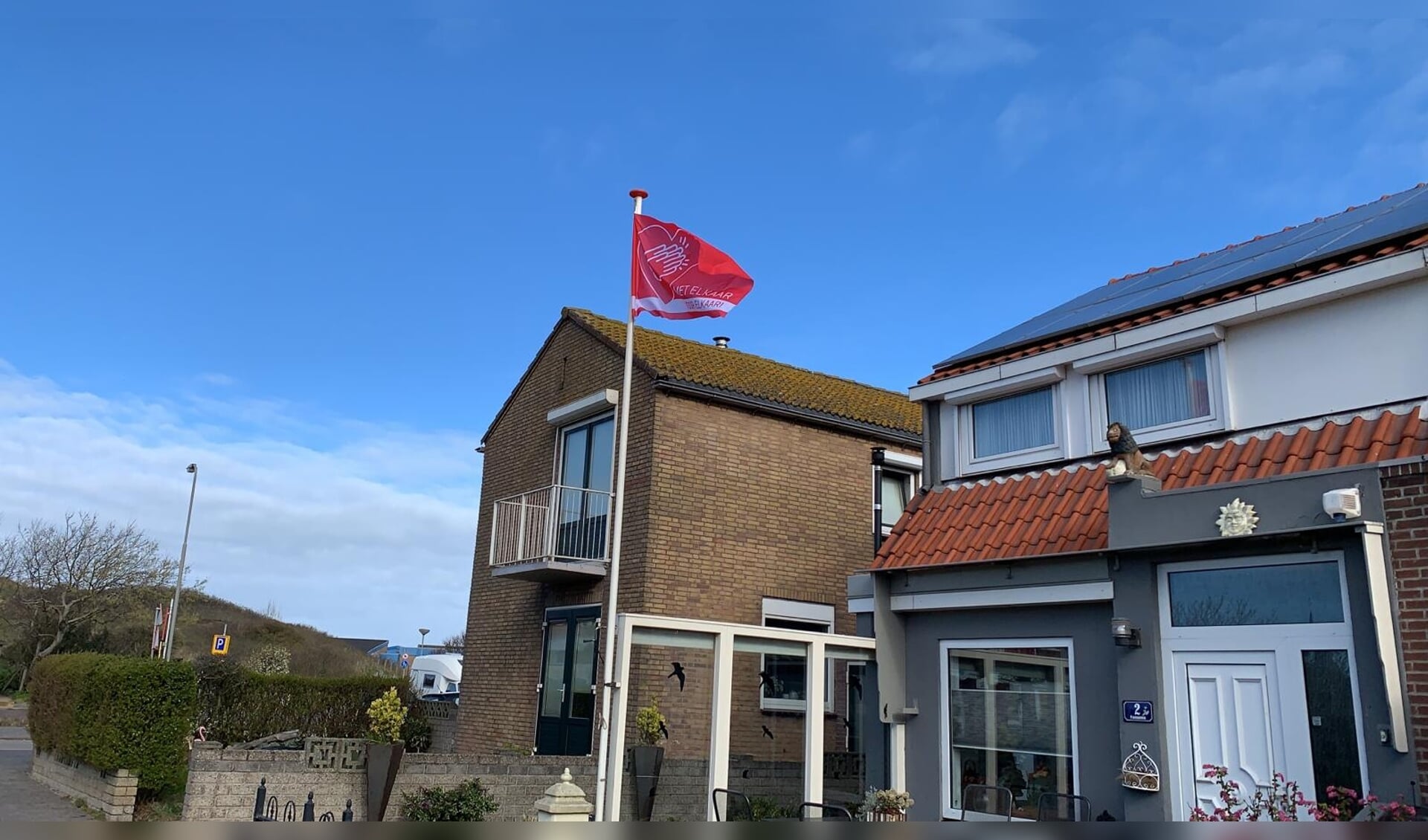 Vlag Met elkaar en voor elkaar wappert ook in Wijk aan Zee.
