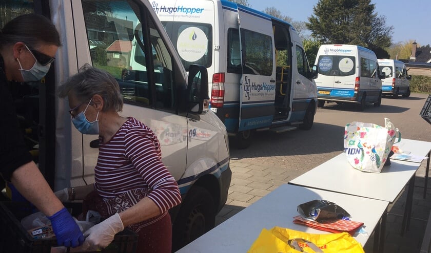 Vrijwilligers sjouwen de pakketten van de Voedselbank in de HugoHopper.