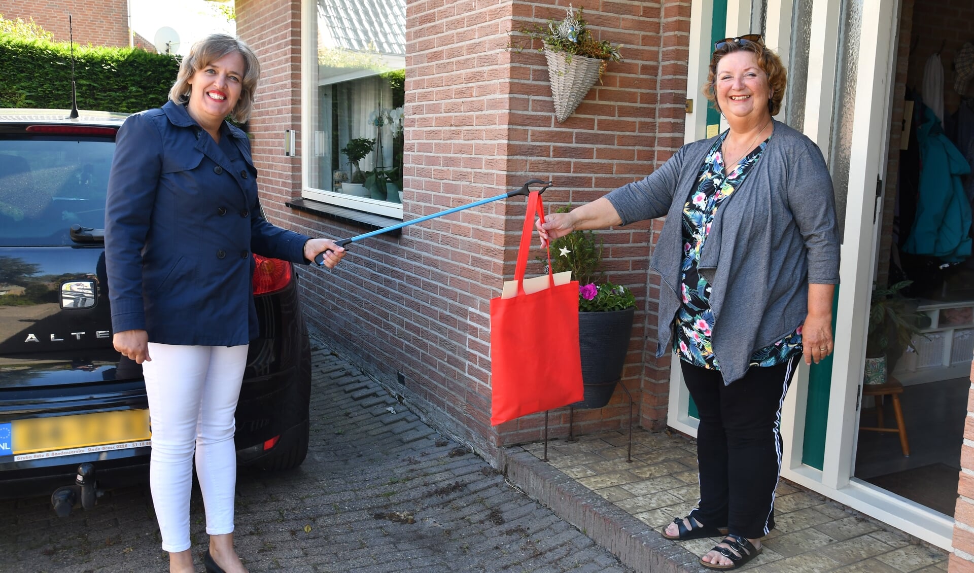 Mevrouw Kenter-de Lange kreeg als eerste het bouwpakket met knutselmateriaal van Wethouder Yvonne Roos-Bakker.