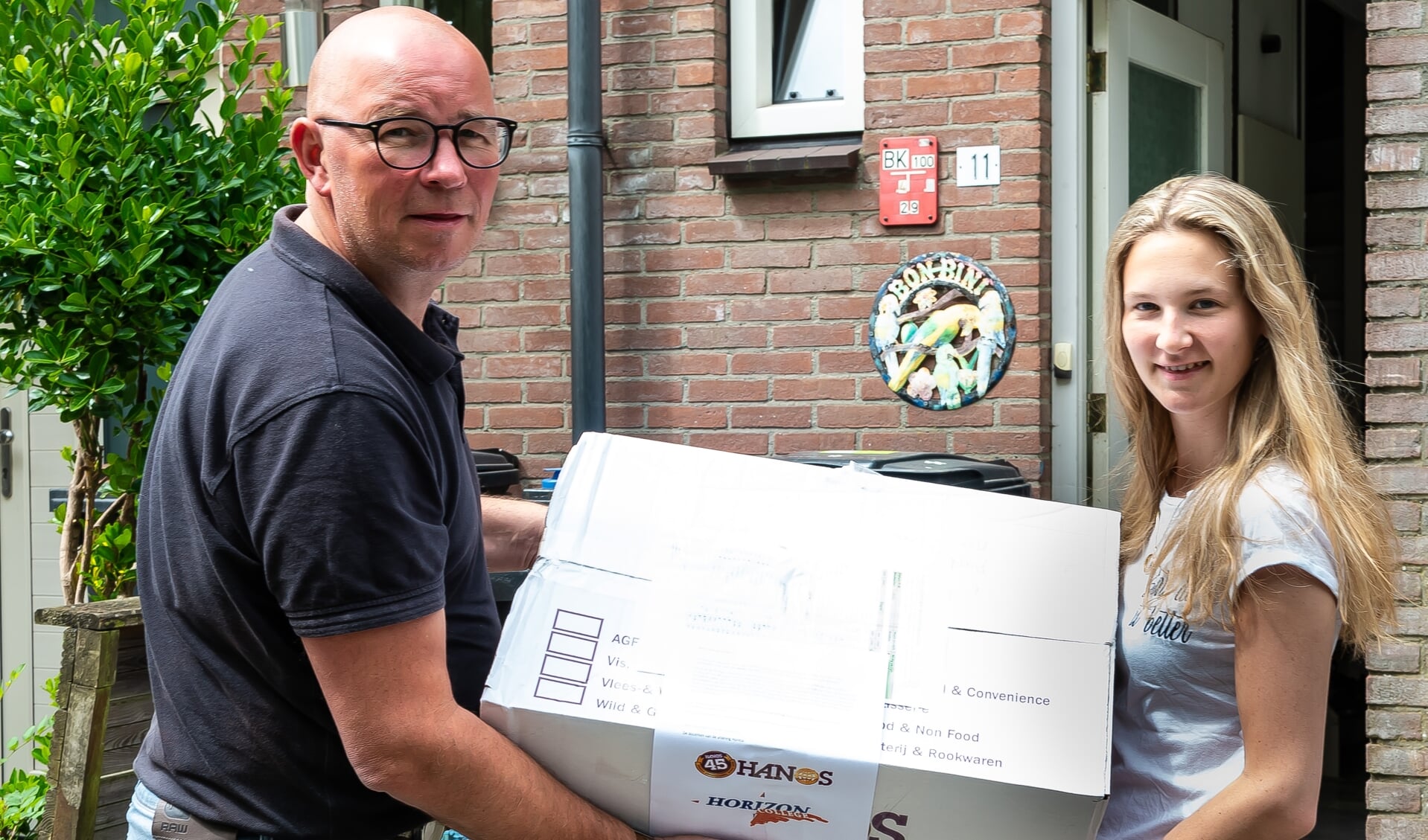 Björn Folkers overhandigt een pakket aan Nicky van Tijn. die examen doet voor  zelfstandig werkend kok.
