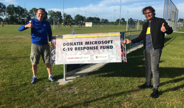 Bram de Putter van CV Wieringermeer en Edwin Wittink van de Hollands Kroonse Uitdaging. Op de achtergrond wordt alweer druk getraind. Op tafel desinfecterende handgel, voorzien van clublogo.