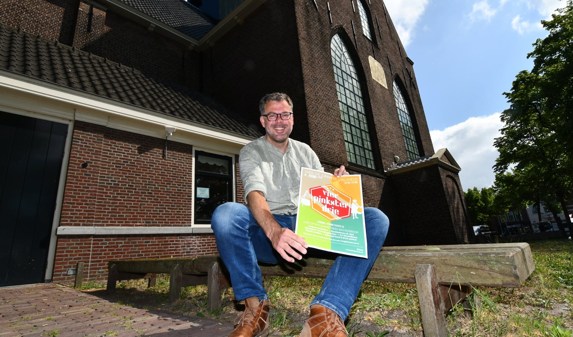 Bas Husslage, met poster 'Ik vier Pinkster drie', voor de Bullekerk op de plek waar ooit een 'schans' was gevestigd. Het is tevens één van locaties die je tegenkomt in de fietstocht.  