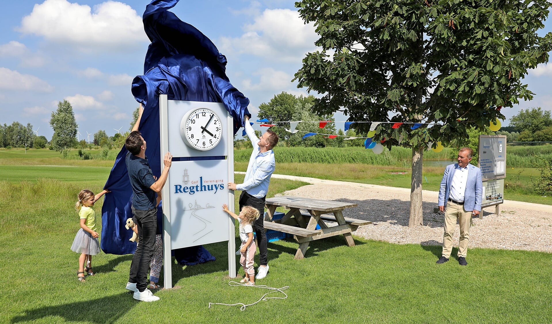 Jeroen Botman en Pieter de Wit onthullen de nieuwe klok onder toeziend oog van de voorzitter van de golfvereniging ’t Regthuys)
