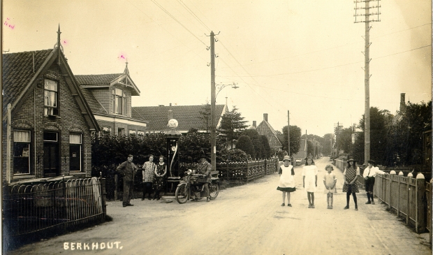 Berkhout omstreeks 1900. Links staat Piet Kool voor zijn garage, naast hem Frouwtje Kool-Bruggen en Bets Eilander. De man op de motorfiets is Willem Smit. In groepje kinderen onder andere Nelie Kommer, Annie Schmidt en Aaf de Haas. Naast de garage de dokterswoning en daarnaast het huis van Jan Maars Nierop.