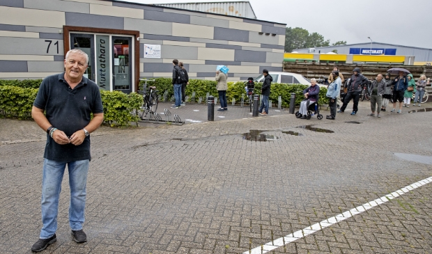 Voorzitter Tim de Heer voor Kringloopwinkel Muttathara, met een lange rij klanten voor de ingang.